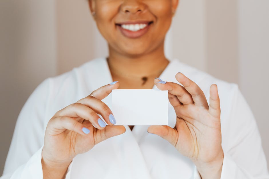 African American woman smiling, holding a blank card in hands, ready for branding or mockup.