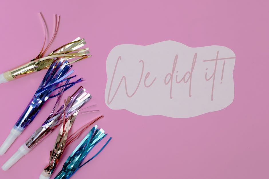 Colorful party blowers and a 'We did it!' message on a pink backdrop, perfect for festive celebrations.