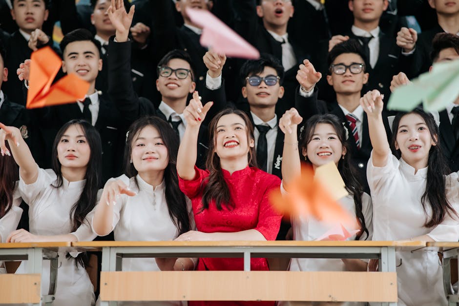 Happy graduates enthusiastically celebrate with paper planes indoors.