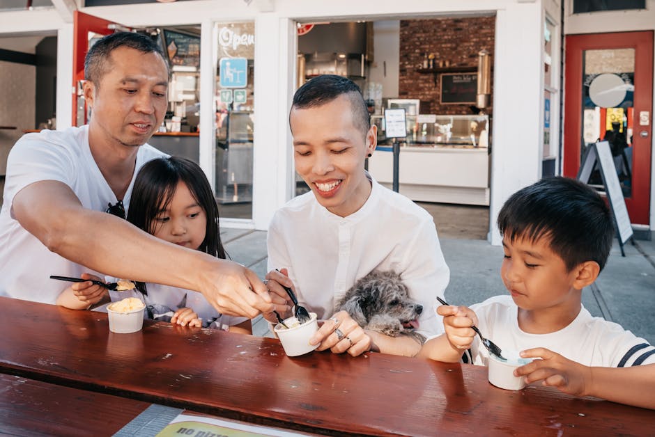 Two fathers with children and a dog enjoying ice cream outdoors, creating joyful family memories.