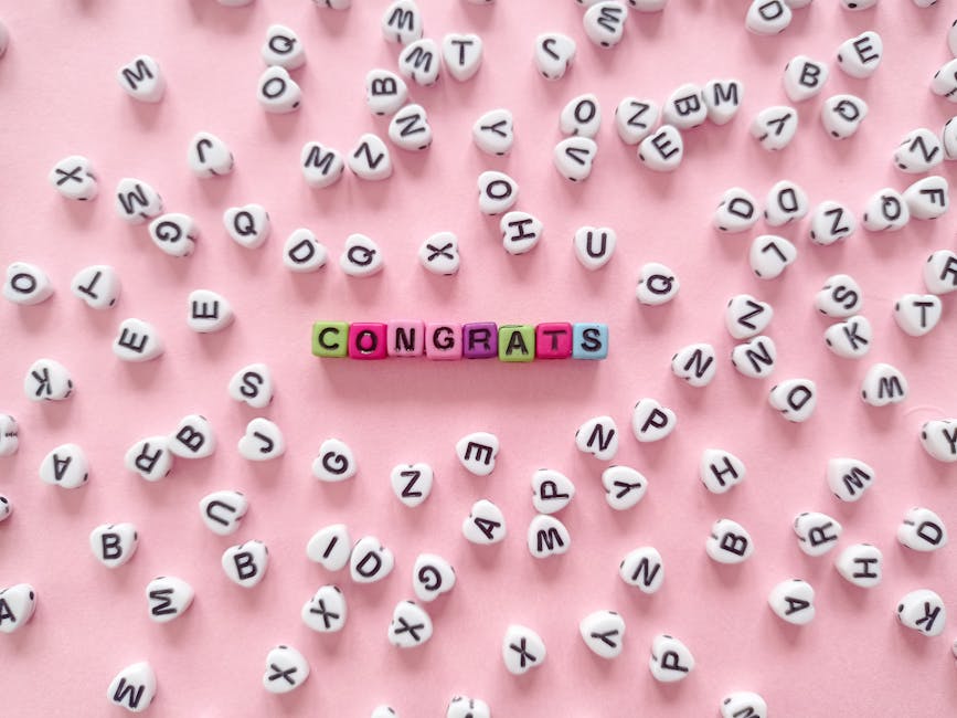 Colorful beads spell 'Congrats' on a pink backdrop with scattered letters.