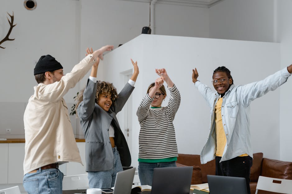 Diverse team celebrates success with enthusiasm in a modern office setting.