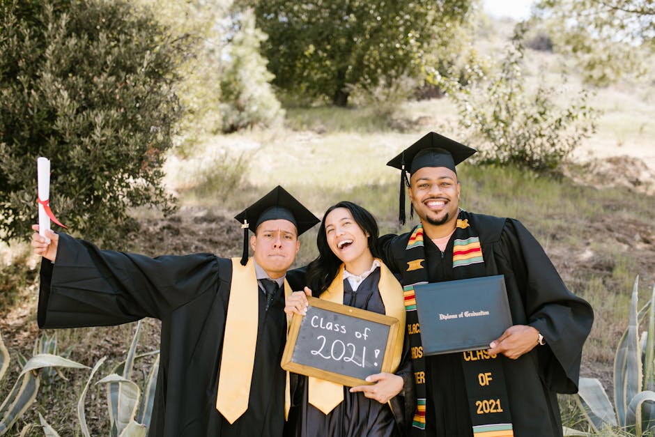 Three graduates celebrating in caps and gowns outdoors, holding diplomas and a 'Class of 2021' sign.