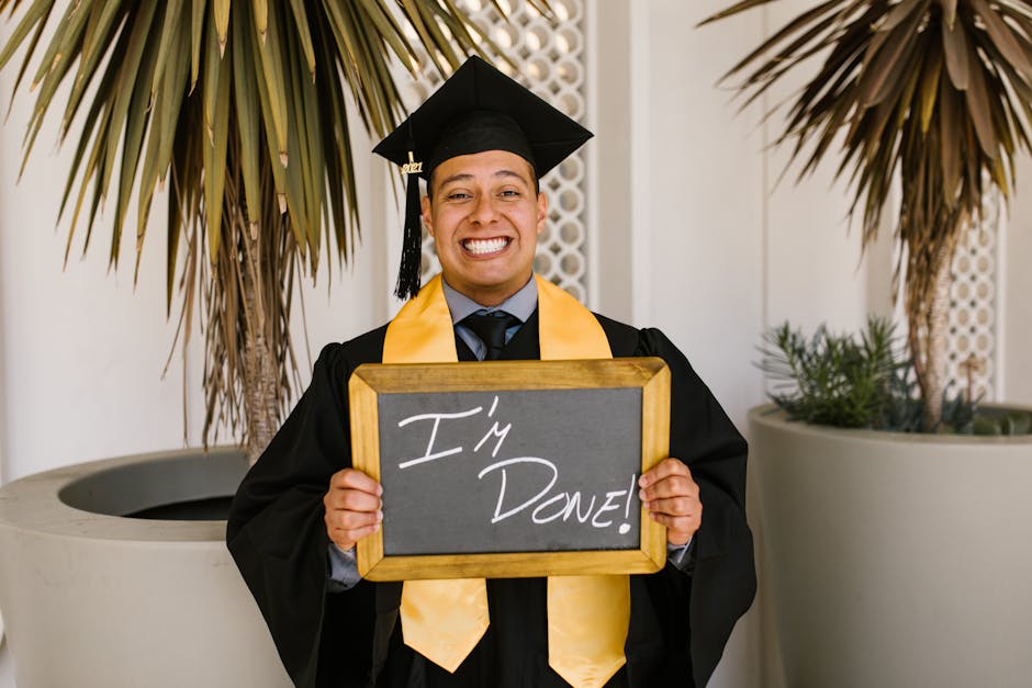 Happy graduate holding chalkboard outside, celebrating achievement in cap and gown.