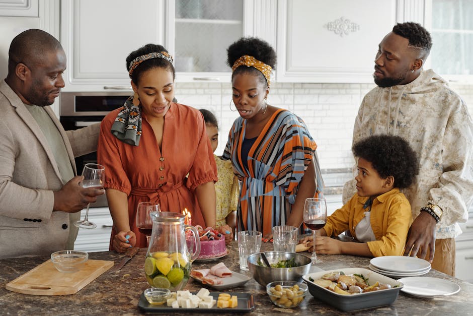 A joyful family gathering around a birthday table with cake and wine in a stylish kitchen.