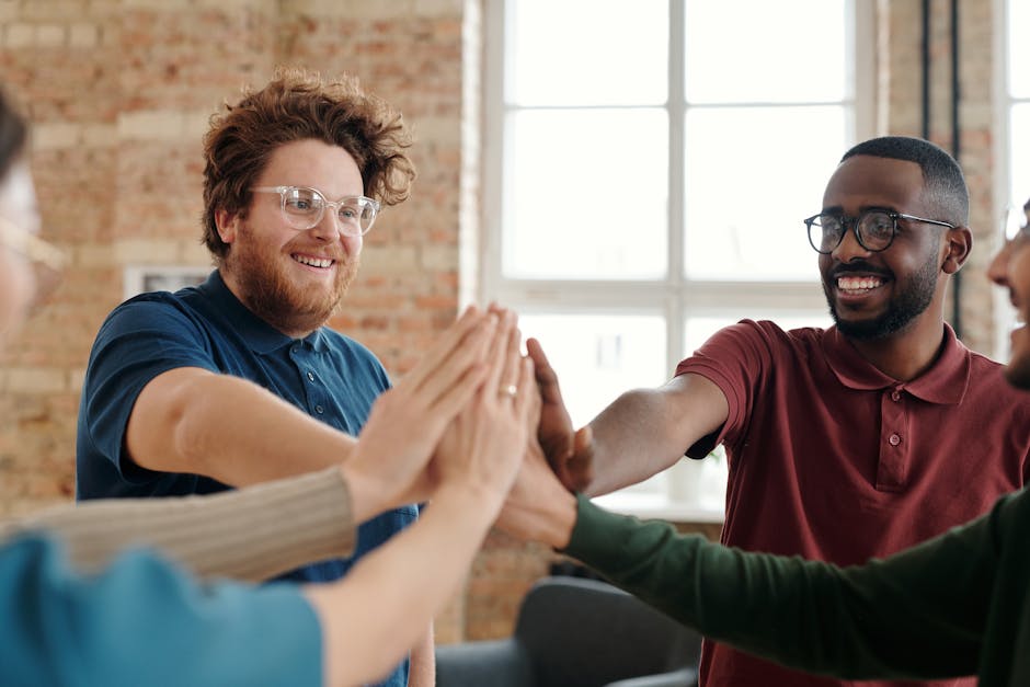 Group of diverse colleagues high-fiving in an office, showcasing teamwork and unity.