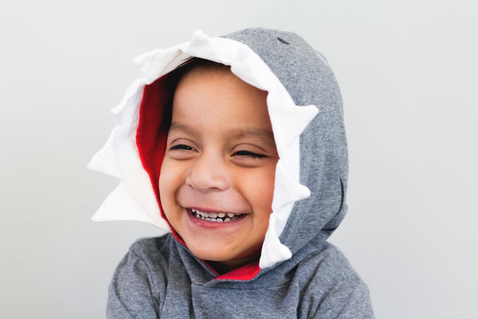 Cute child wearing a shark-themed hoodie, smiling joyfully. Perfect for playful and happy themes.