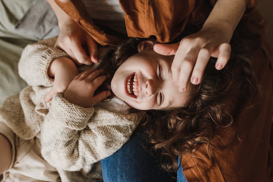 A happy child laughing while being playfully tickled by a parent indoors.
