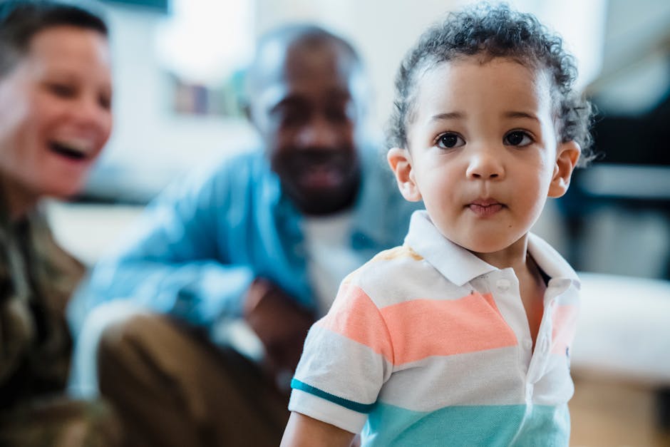 A young child in focus with smiling adults in the background. Heartwarming family scene.