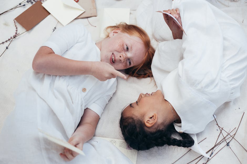 Two girls playing and laughing on a blanket, embodying happiness and friendship.