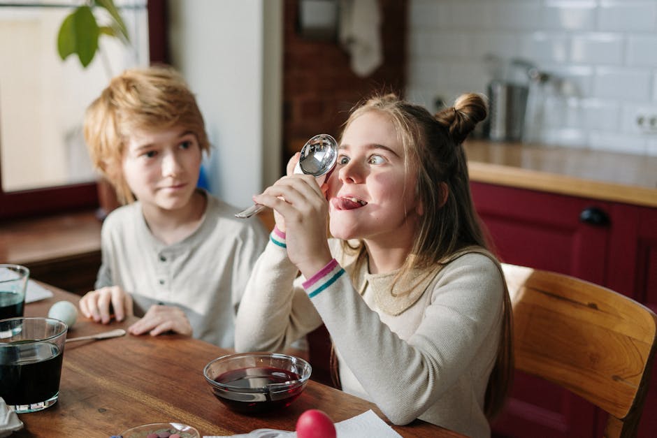 Two kids having fun decorating Easter eggs with creative humor in a cozy kitchen setting.