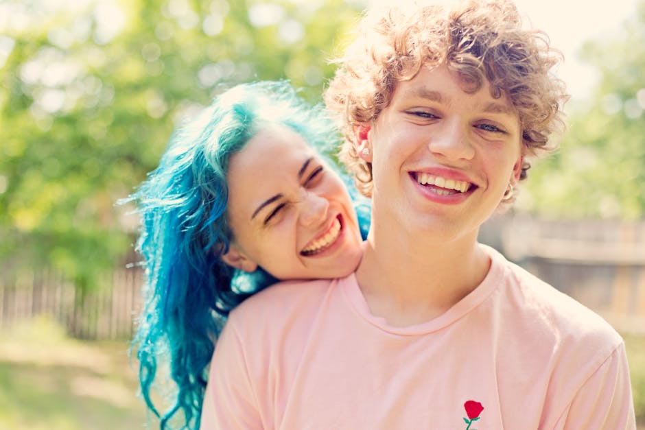 A happy couple with bright hair, embracing outdoors on a sunny day, showcasing love and joy.