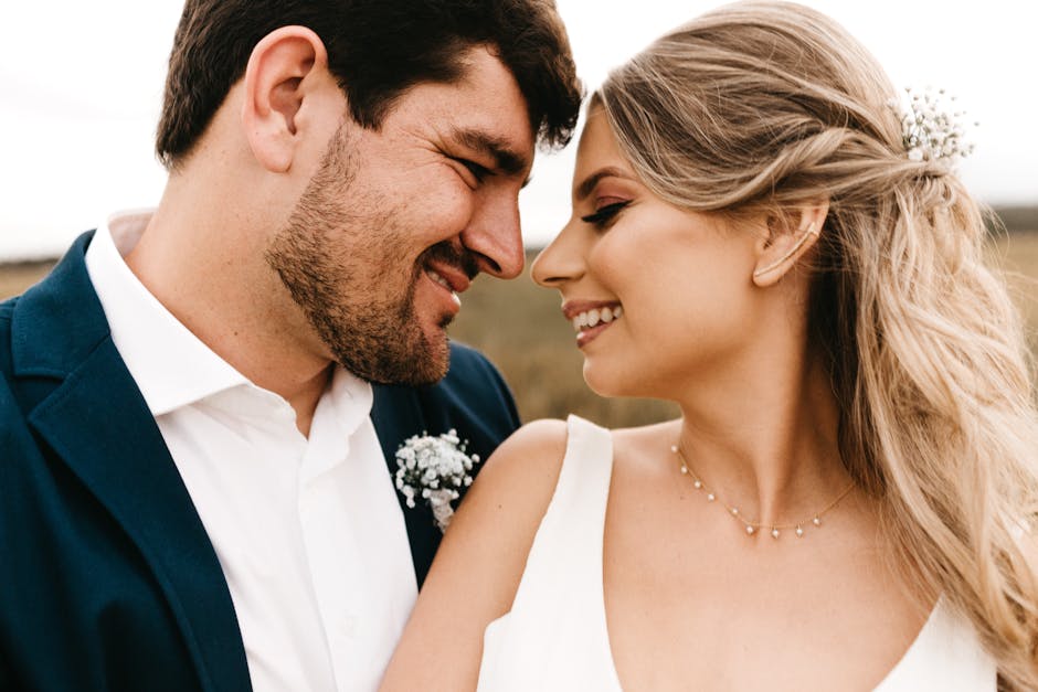 A close-up portrait of a joyful bride and groom embracing in an outdoor setting, capturing their happiness and love.