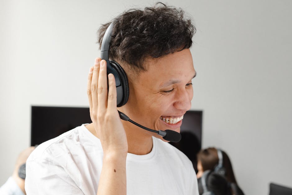 Portrait of a cheerful call center agent wearing a headset, smiling while working in an office environment.