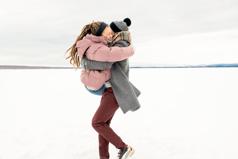 A couple joyfully embracing on a snowy winter day outdoors. Warm clothing and happiness.