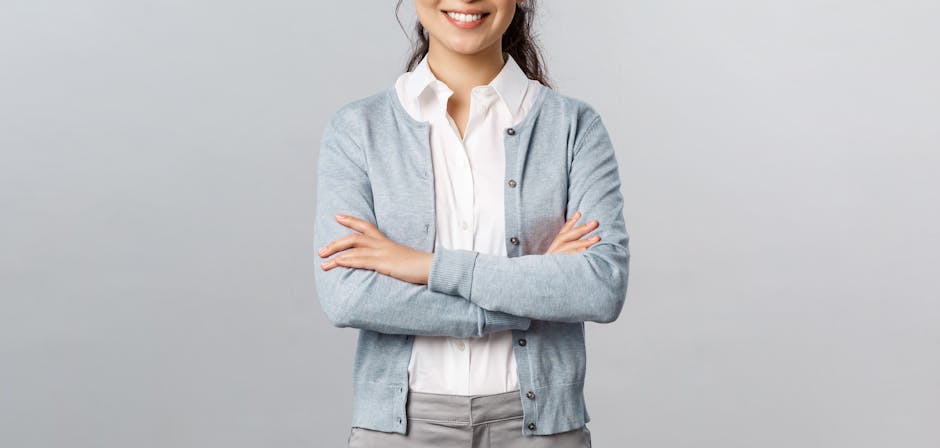Portrait of a confident woman wearing a cardigan and smiling with arms crossed.