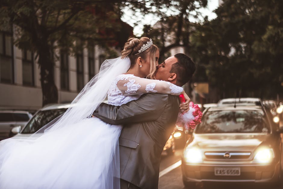 Bride and groom kissing passionately in a city street after their wedding ceremony.