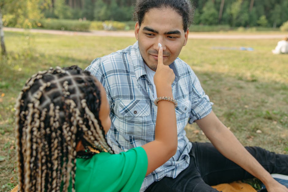 A father and daughter enjoying a playful moment together in a sunny park setting.