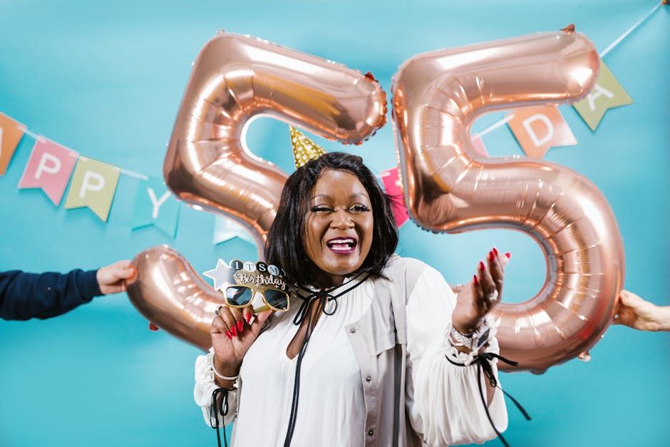 Smiling woman celebrates 55th birthday with balloons and festive decor.