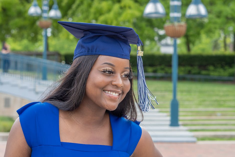 Smiling woman in blue graduation gown outdoors during ceremony in Columbia, MD.