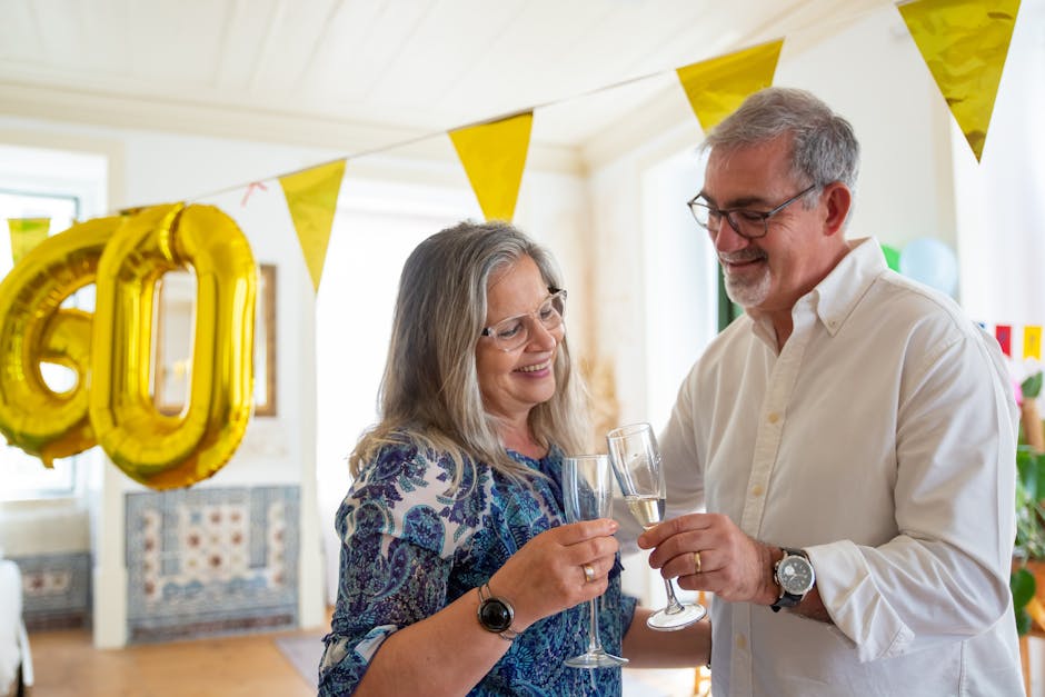 Elderly couple toasting at a 60th birthday party with festive decor and champagne.