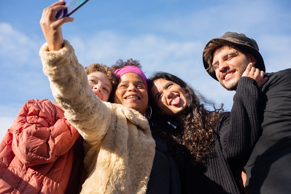 A joyful group of diverse friends taking a selfie outdoors on a sunny day.