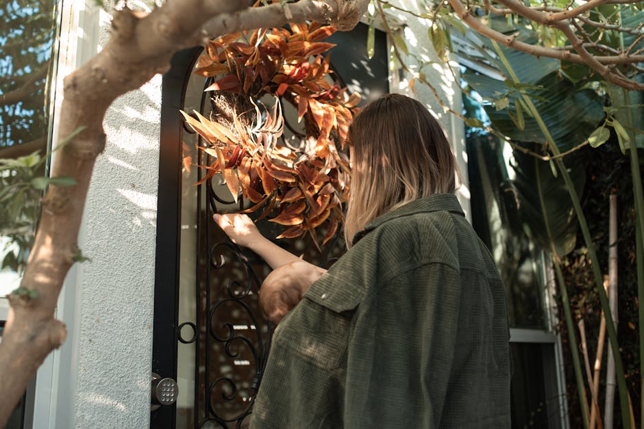 Woman and child enjoy a warm autumn day, reaching for a front door wreath.