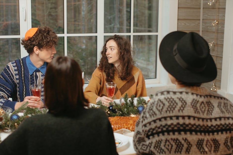 Friends gather indoors around a festive table, enjoying food and conversation during a holiday celebration.