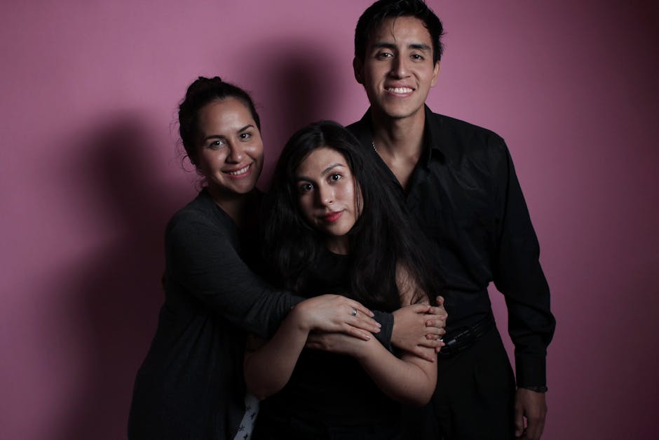 Portrait of friends smiling in front of a pink background, capturing joy and togetherness.