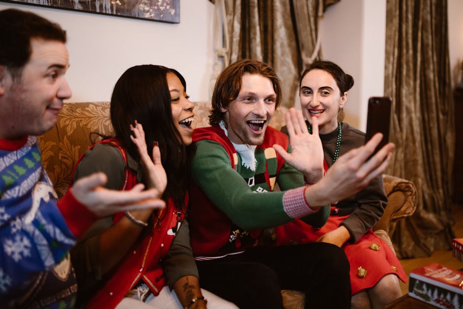 Group of friends in festive sweaters taking a cheerful selfie indoors.