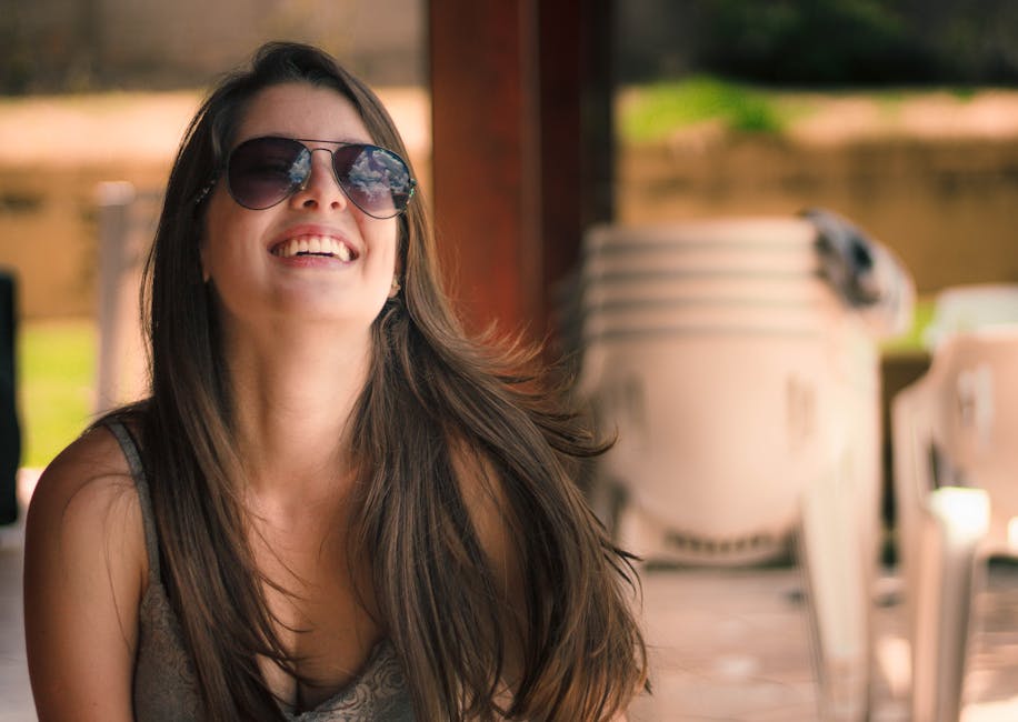 Smiling woman enjoying a sunny day outdoors with sunglasses.