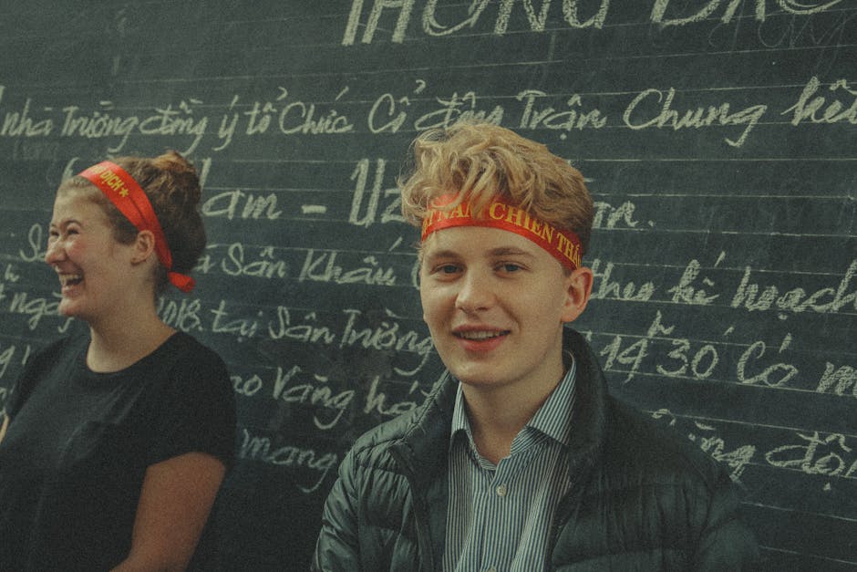 Two young adults smiling in front of a Vietnamese chalkboard.