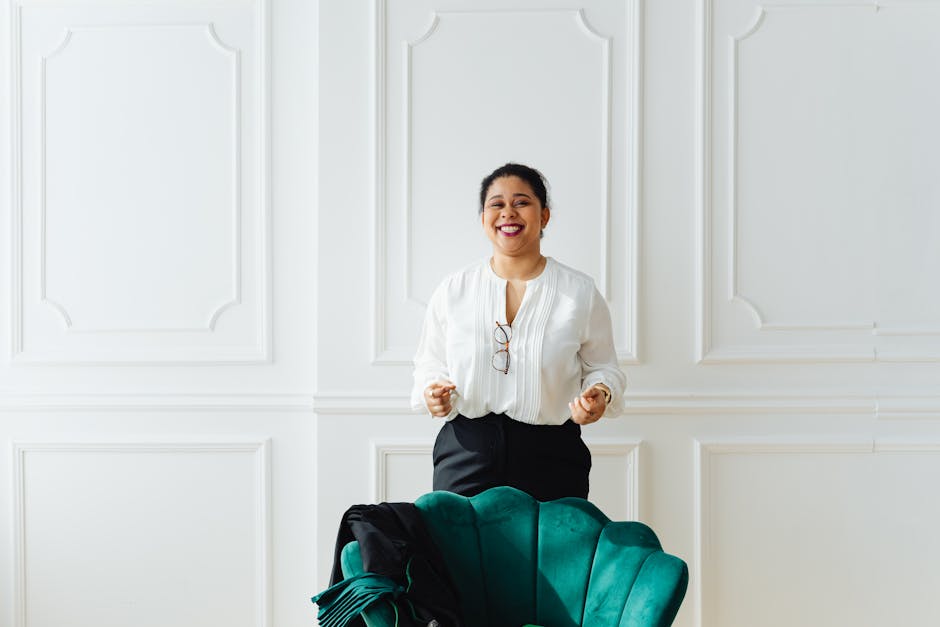 Happy woman standing in a stylish white room, smiling at the camera.