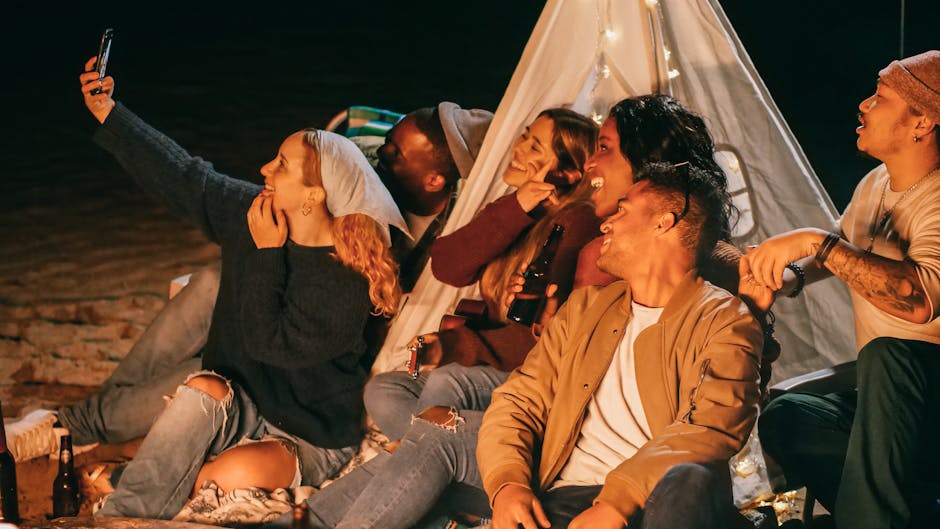 A diverse group of friends enjoying a lively beach night party, capturing memories with a selfie.