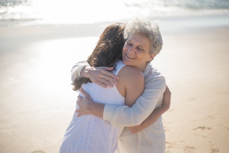 A joyful moment of togetherness as a mother and daughter share a warm embrace on a sunny beach day.