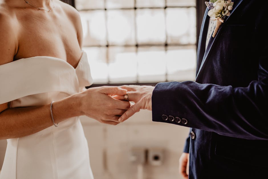 Close-up of wedding couple exchanging rings during a ceremony indoors.