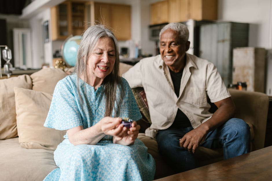 Two senior adults enjoying a light moment indoors, sitting comfortably on a couch.