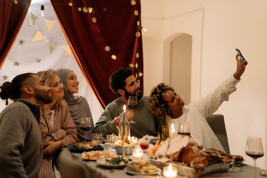 Group of diverse friends enjoying a festive meal indoors and capturing the moment with a selfie.