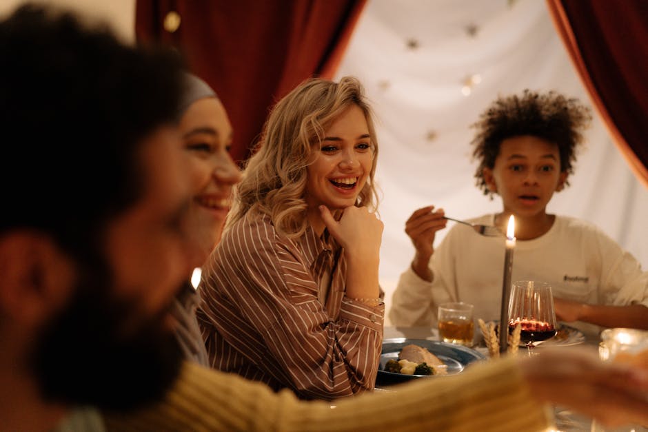A warm, joyful dinner gathering indoors with diverse friends and family sharing food and laughter.