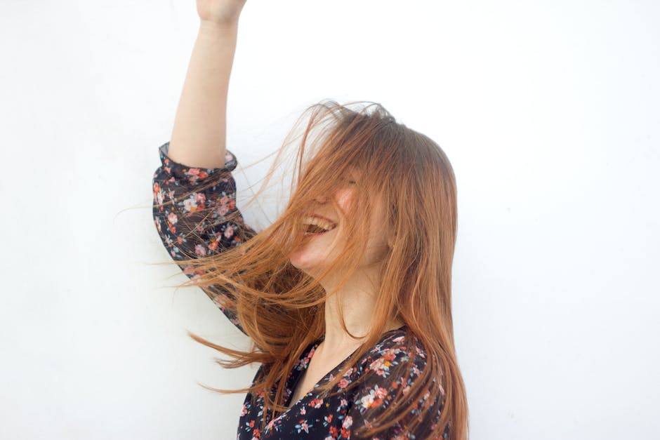 A cheerful woman with red hair joyfully laughing against a clean white background.