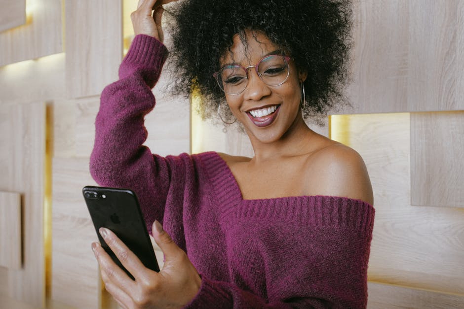 Happy woman with afro hairstyle using smartphone for a video call indoors.
