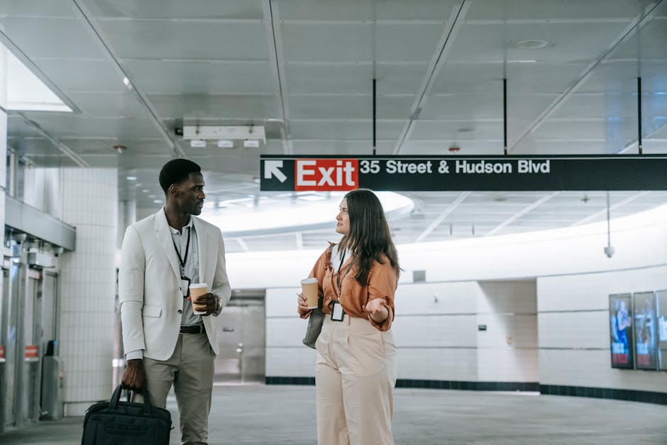 Two office workers engage in conversation at a modern subway station.