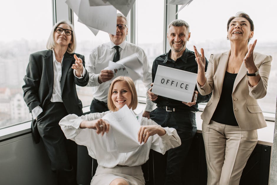 A diverse group of business professionals joyfully celebrating in an office setting, symbolizing teamwork.