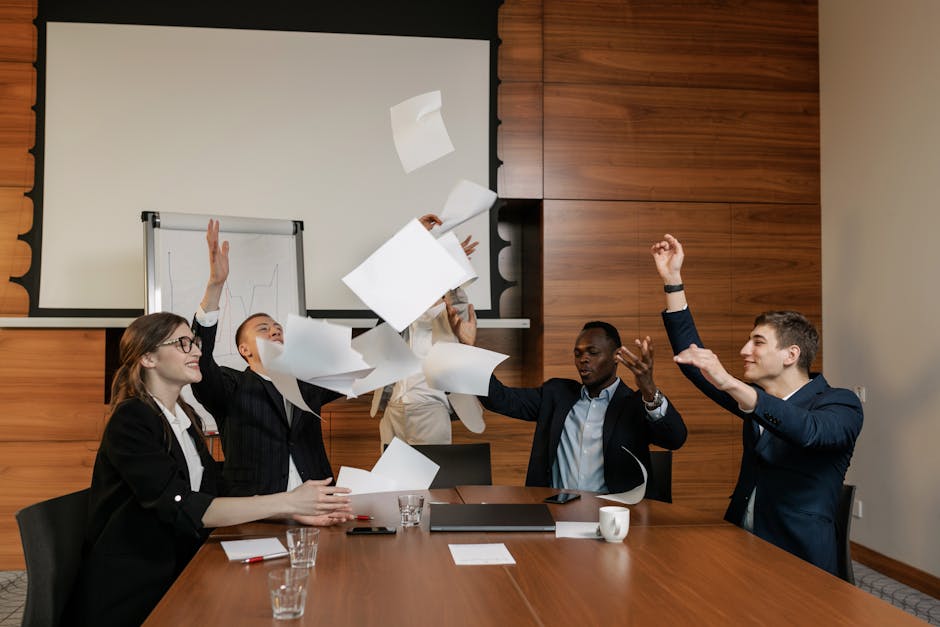 A diverse group of office workers joyfully tossing papers in a modern conference room.